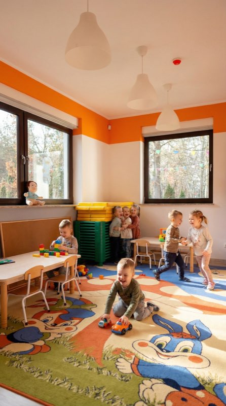 Dzieci grają w sali z kolorowymi klockami